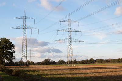 Electricity pylon on field against sky