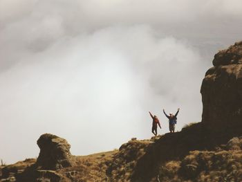 People on rock formation against sky