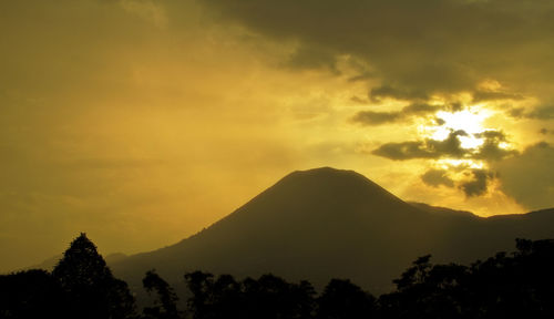 Low angle view of silhouette mountains against orange sky