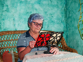 Woman reading book while sitting on sofa at home