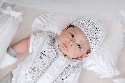 Portrait of cute baby lying on bed at home