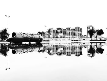 Reflection of buildings in lake against clear sky