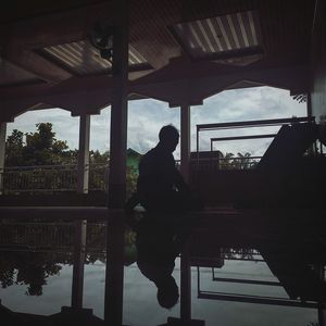 Silhouette man standing by bridge against sky