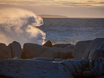 Scenic view of rocks at beach during sunset