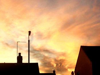 Low angle view of silhouette building against cloudy sky