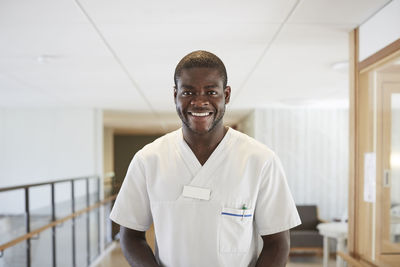 Portrait of happy male nurse standing in hospital