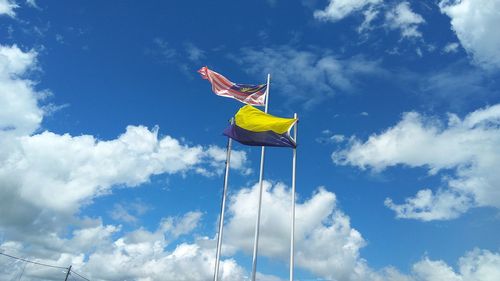 Low angle view of flags against blue sky during sunny day