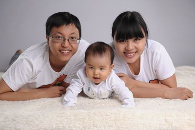 Portrait of smiling family on rug against white background