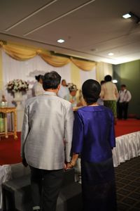 Rear view of couple walking towards stage in reception hall
