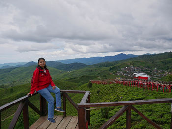 Full length of woman standing on railing against mountain