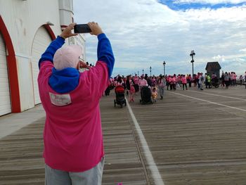 Rear view of people walking on road against sky