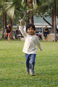 Portrait of boy holding pinwheel while walking on field