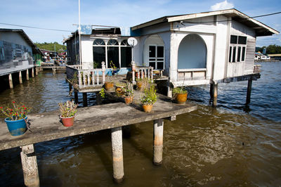 Wooden posts in lake by building against sky