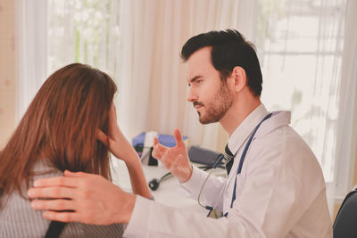 Doctor consoling female patient at clinic