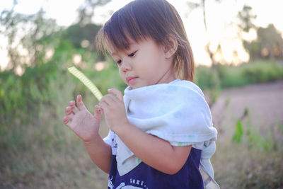 Girl holding plant pod while standing on land