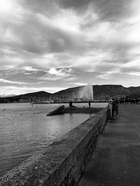 Bridge over sea against cloudy sky