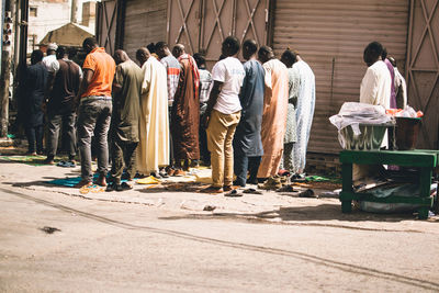 Rear view of people praying on street