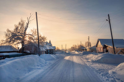 Snow covered field against sky during sunset