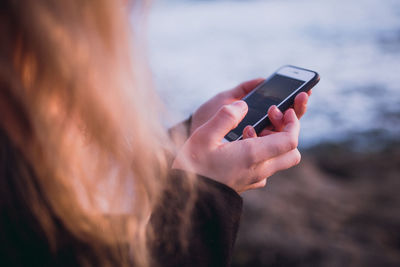 Close-up of woman using mobile phone at beach