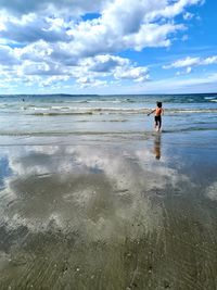 Rear view of boy on beach against sky