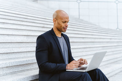 Young man using laptop while sitting on steps