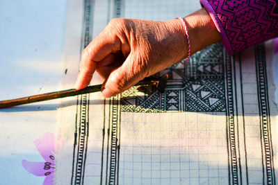 Cropped hand of senior woman making design on fabric