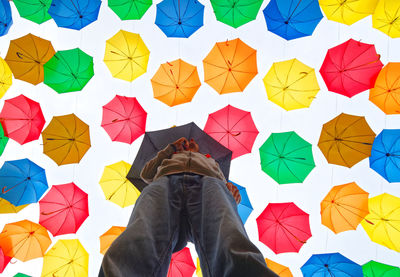 Directly below shot of man standing against colorful umbrellas