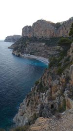 Rock formations by sea against clear sky