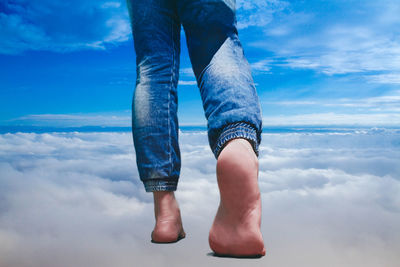 Low section of man standing against blue sky