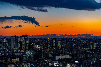 Illuminated cityscape against sky during sunset