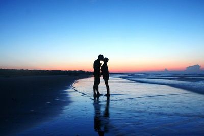 Silhouette man standing on beach against sky during sunset