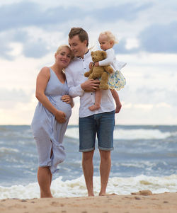Pregnant woman with man and daughter at beach