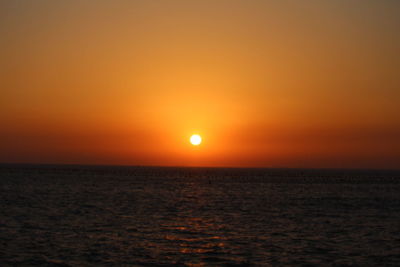 Scenic view of sea against dramatic sky during sunset