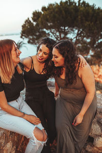 Happy friends sitting on stone wall