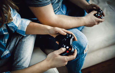 Midsection of people holding video game controller at home