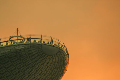 Low angle view of people standing at observation point during sunset