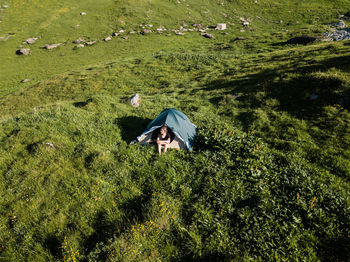 Woman sitting under tent on grassland