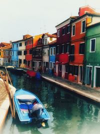 Boats moored in canal by buildings in city against sky