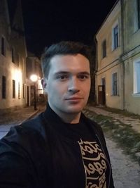 Portrait of man standing in alley amidst buildings