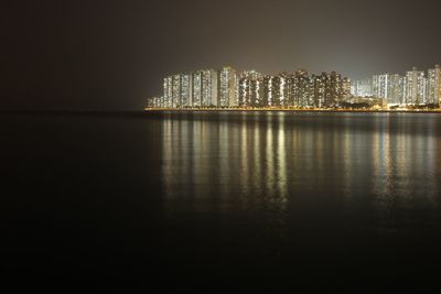 Illuminated city at waterfront at night