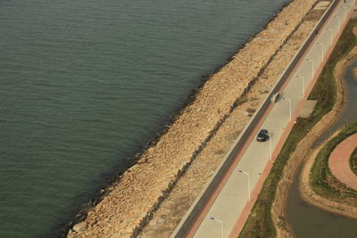 High angle view of sea by road on sunny day