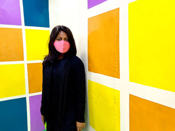 Portrait of young woman standing against wall