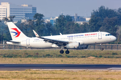 Airplane flying over airport runway against sky