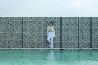Portrait of woman standing on poolside against sky