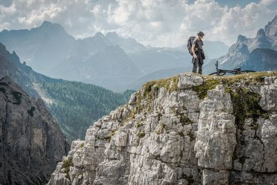 Mid adult man standing on mountain against cloudy sky