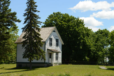 Trees and house on field against sky