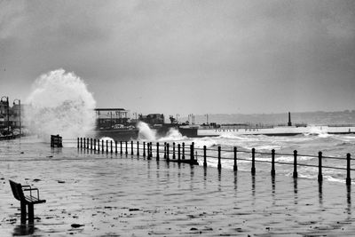 Wooden posts on pier by sea against sky