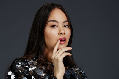 Portrait of young woman against black background