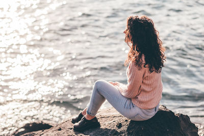 Side view of woman sitting on rock
