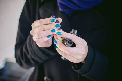 Midsection of woman holding electronic cigarette and dropper